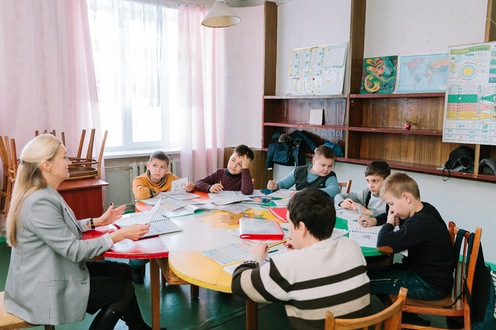 Викладачка та група дітей працюють із навчальними матеріалами за спільним столом