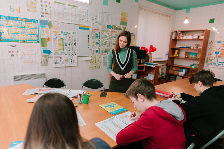 Викладачка допомагає учням працювати з навчальними картами в класі